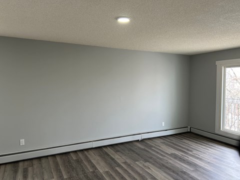 an empty living room with wood floors and a large window