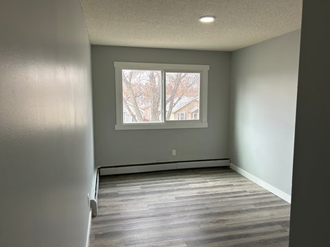 an empty room with a window and wooden floors