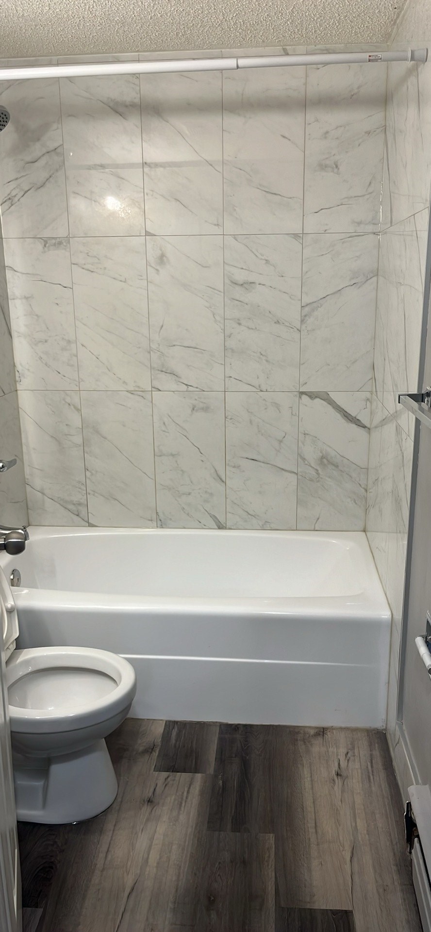 A white toilet sits next to a white bathtub in a bathroom.