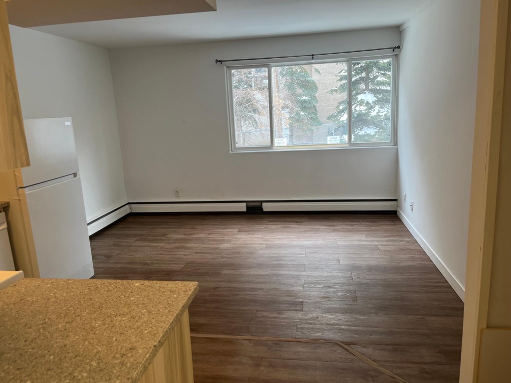 A kitchen with a white refrigerator and brown wooden floors.
