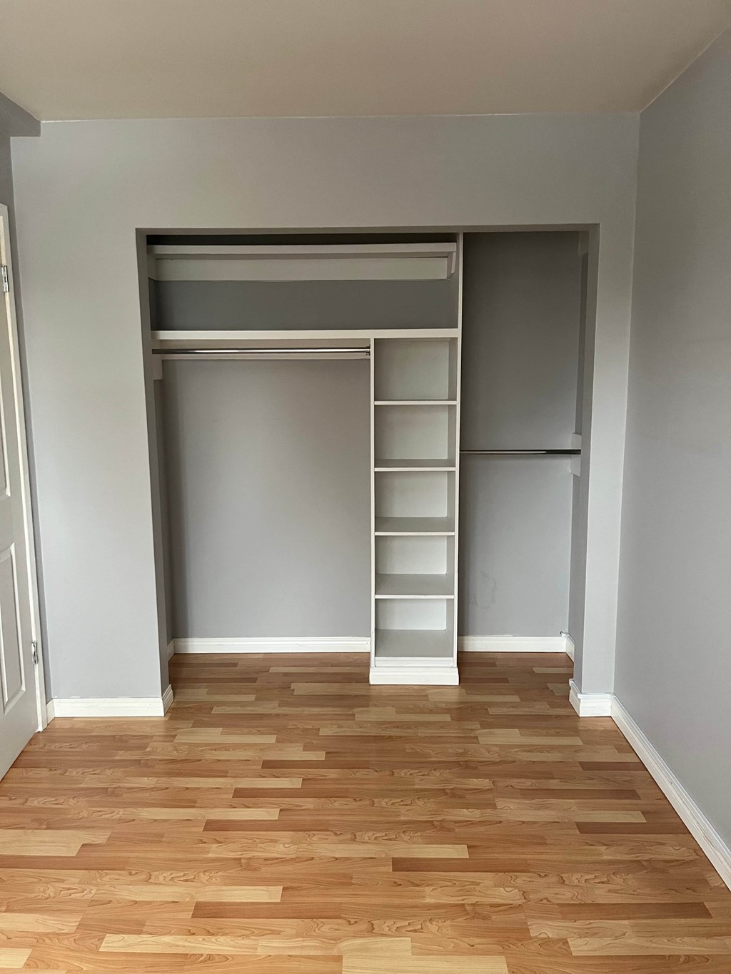 A room with a wooden floor and a white closet with shelves.
