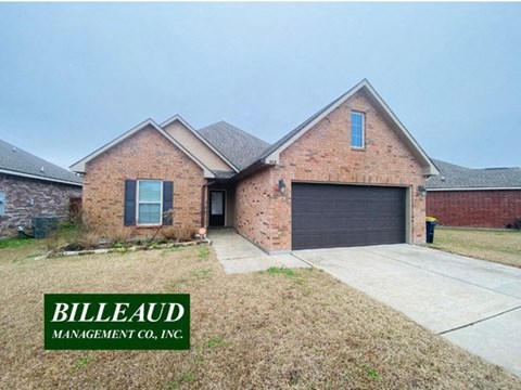 A brick house with a garage door and a sign that says Billeaud Management Co., Inc.