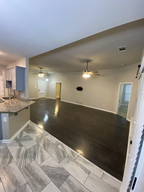 A spacious room with a marble floor and a ceiling fan.