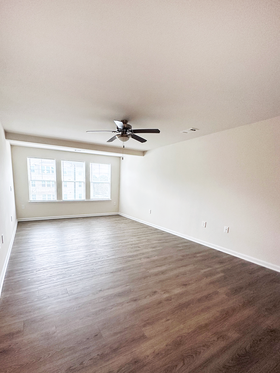 an empty living room with wood floors and a ceiling fan