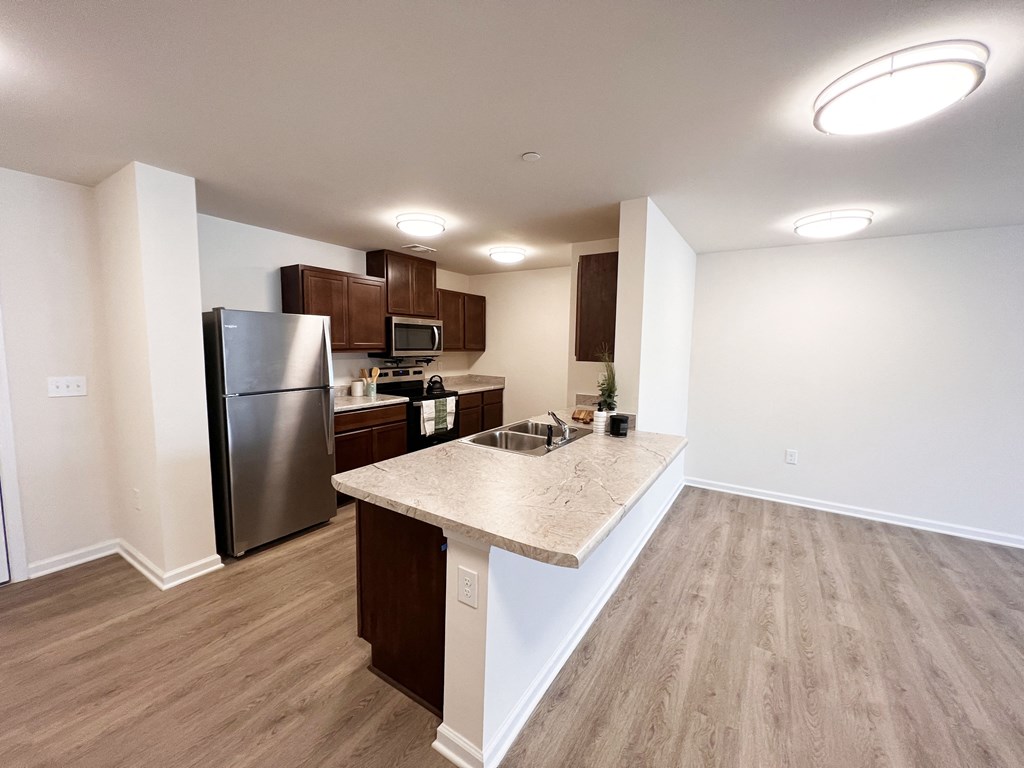 a kitchen with stainless steel appliances and a marble counter top in an empty apartment