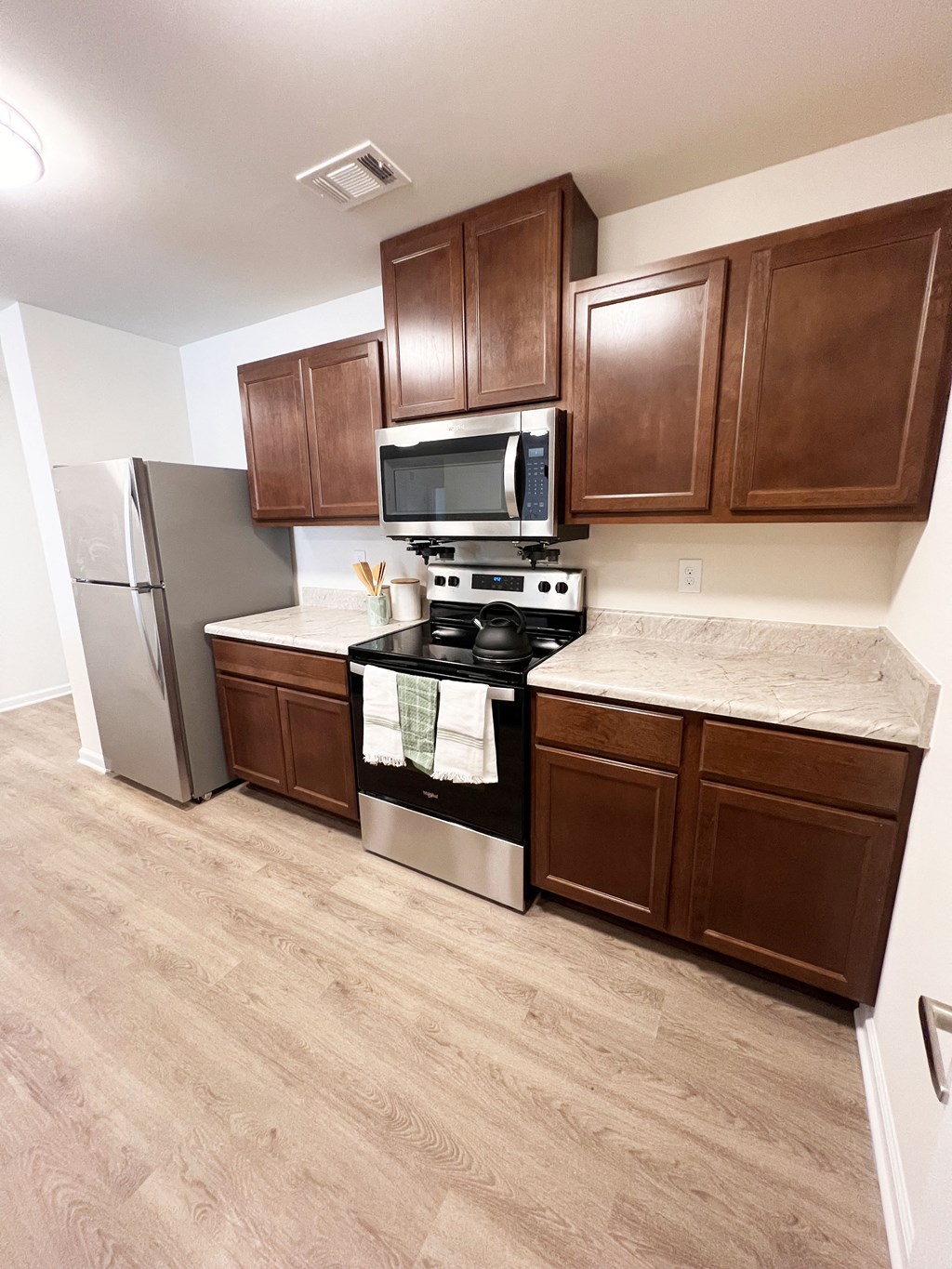 an empty kitchen with wooden cabinets and stainless steel appliances