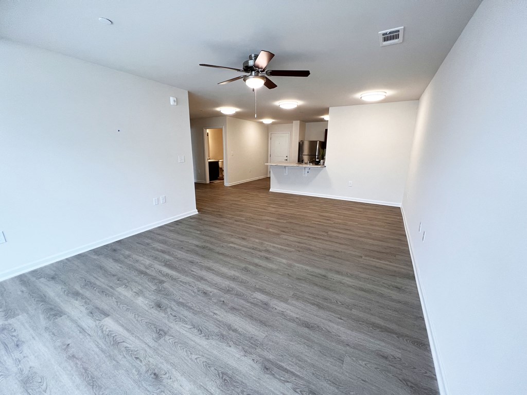 an empty living room with wood flooring and a ceiling fan