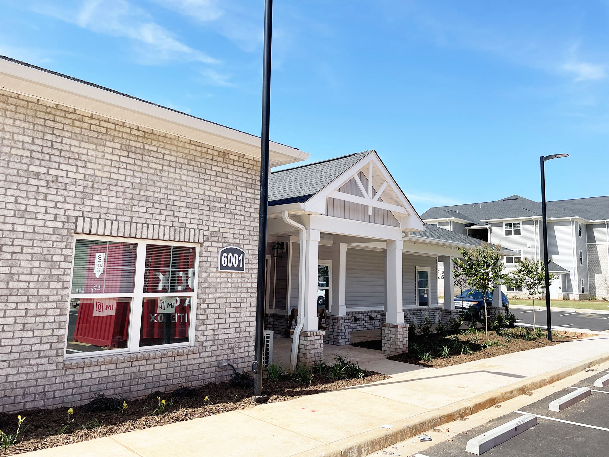 the front of a brick building with a red door and a porch