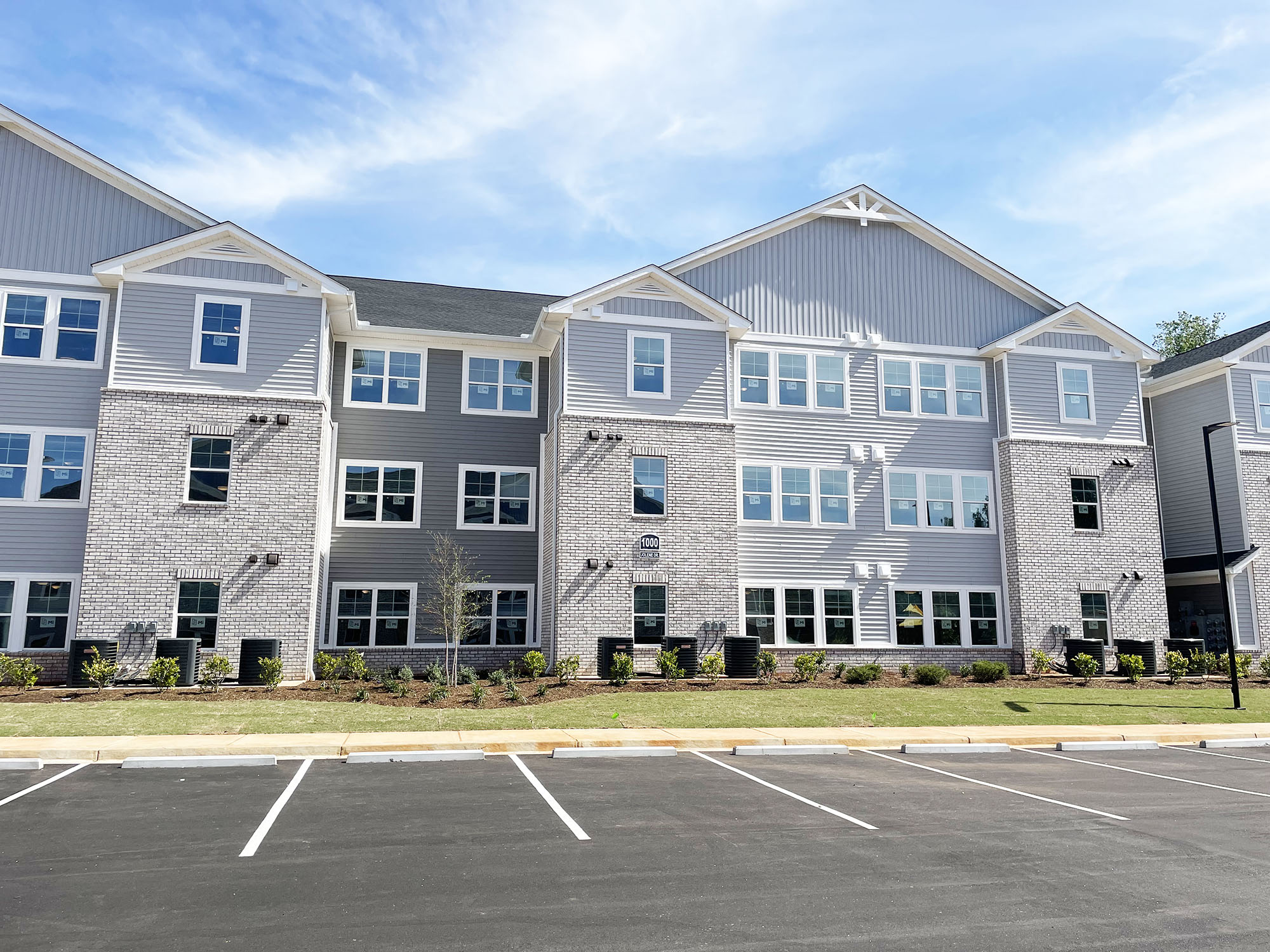the exterior of an apartment building with a parking lot