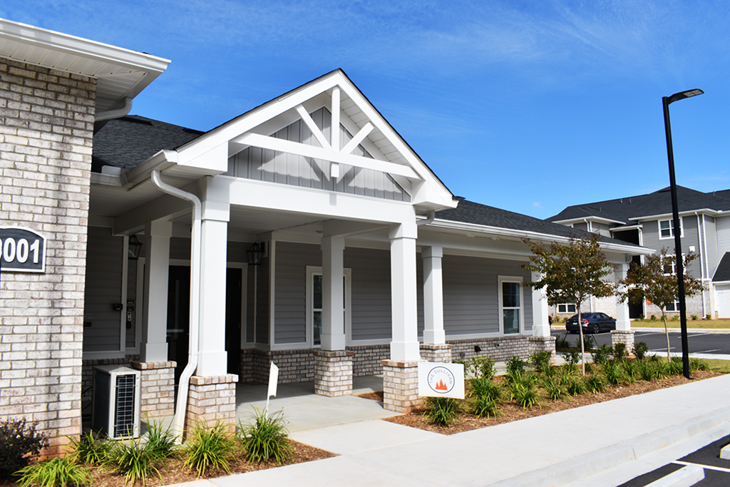 the front of a grey house with a white sign in front of it
