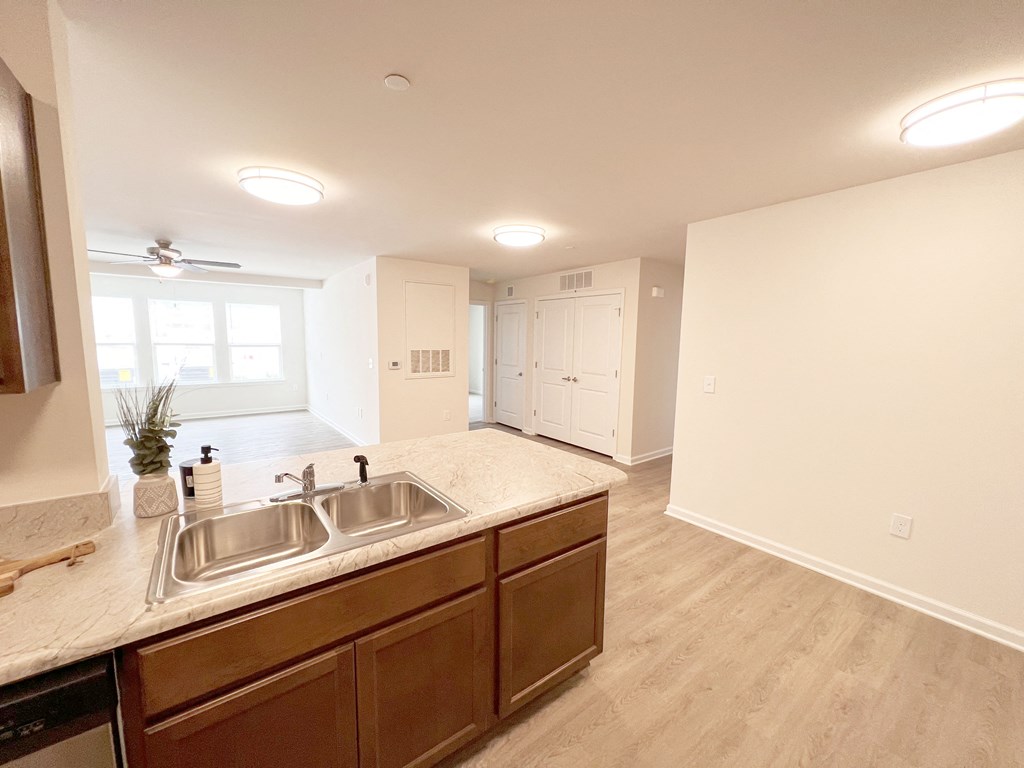 an empty kitchen and living room with a large window and a sink