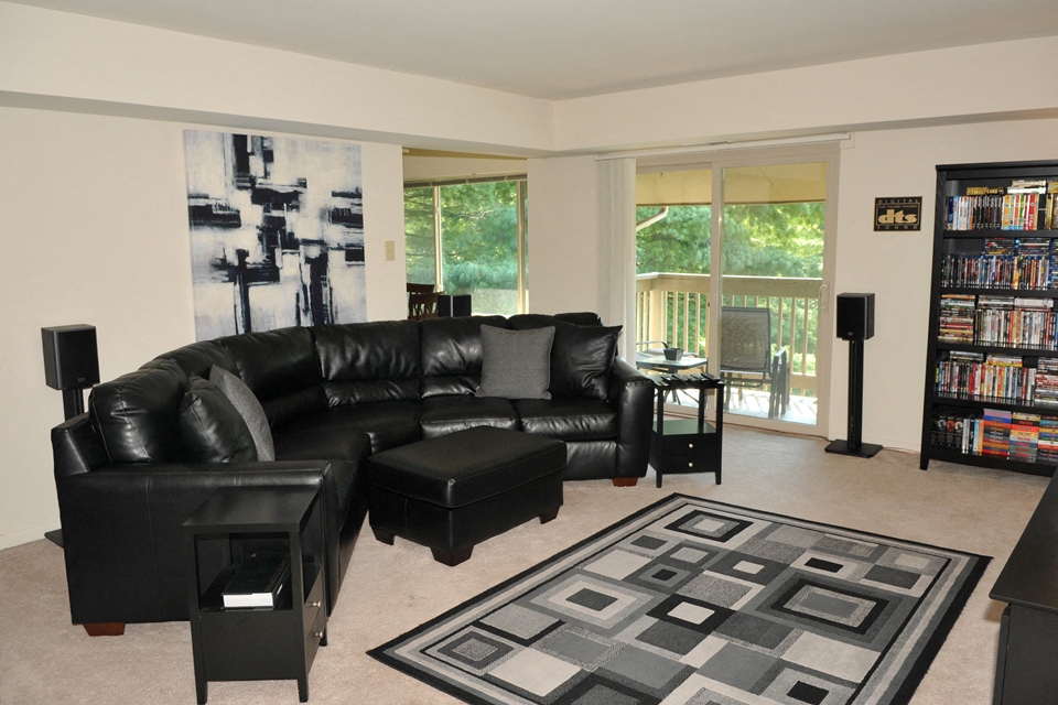 a living room with black leather furniture and a large rug