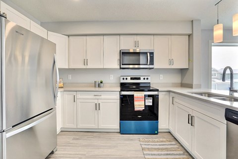 an empty kitchen with white cabinets and stainless steel appliances