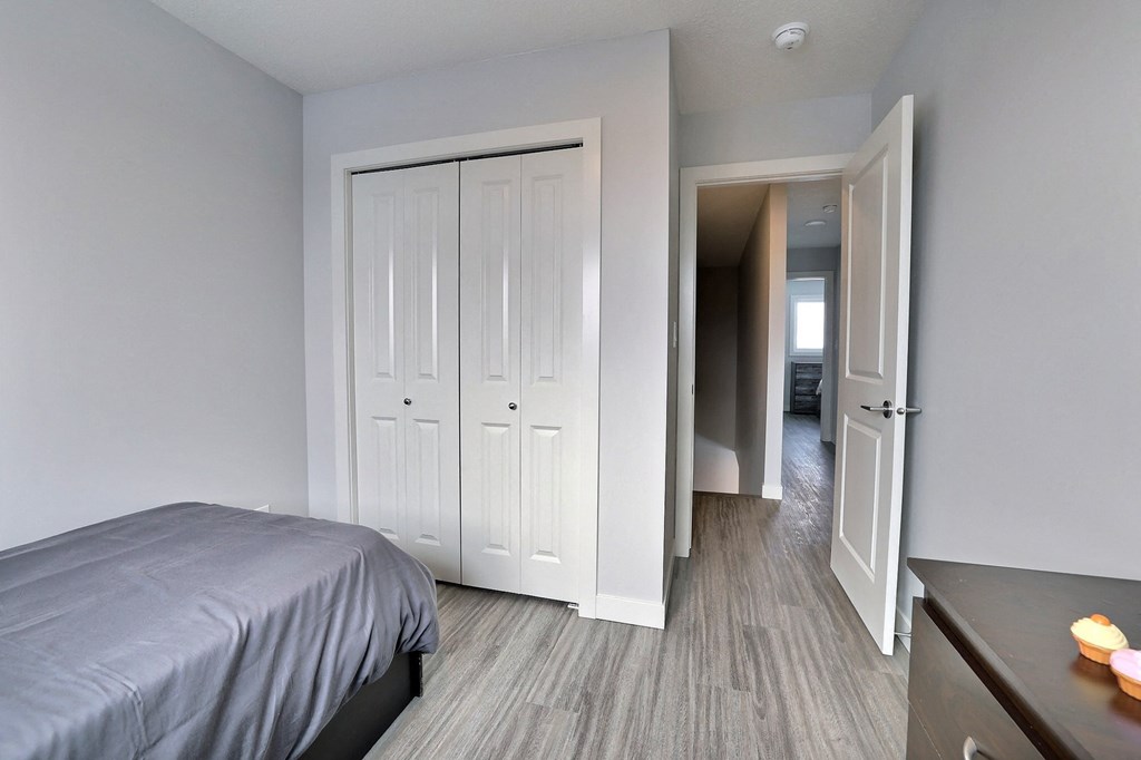 a bedroom with a bed and a closet and a door to a hallway