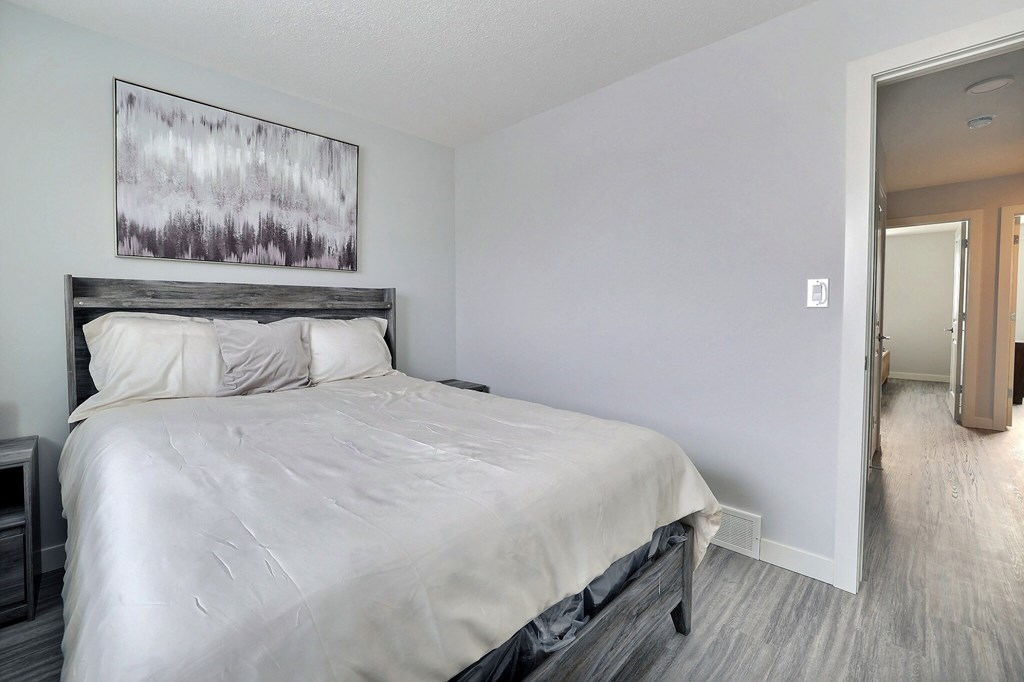 a bedroom with a white bed and a painting on the wall