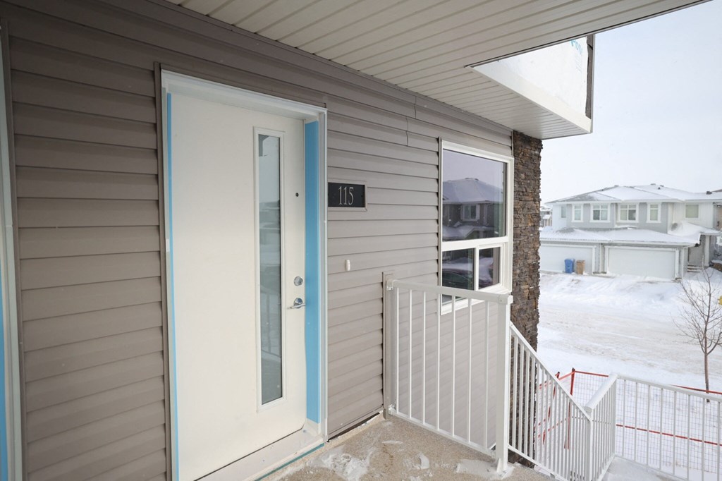 the front door of a home with a white railing and a glass door open