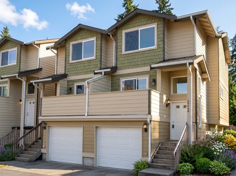 Ballinger Place townhome exterior with a private front door, steps, attached garage, and flowering garden beds.