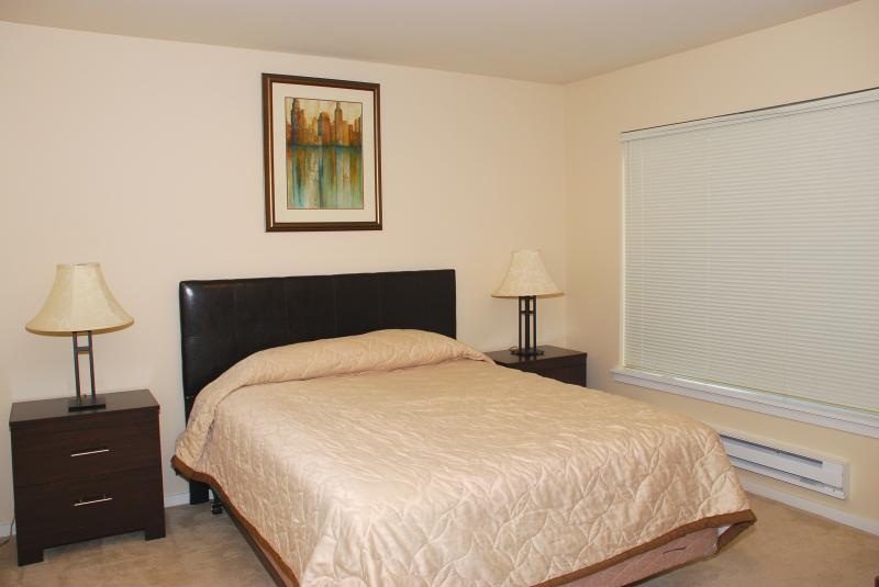 A bedroom with a bed, two lamps, and a picture on the wall.