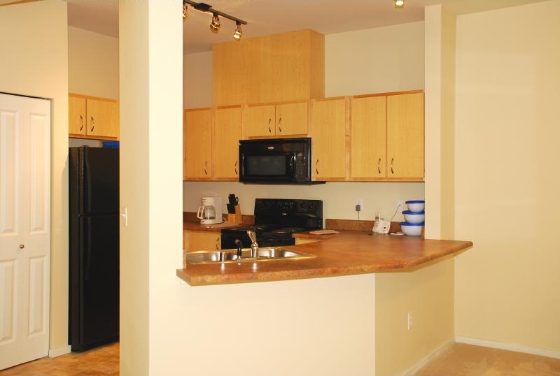 A kitchen with wooden cabinets and a black refrigerator.
