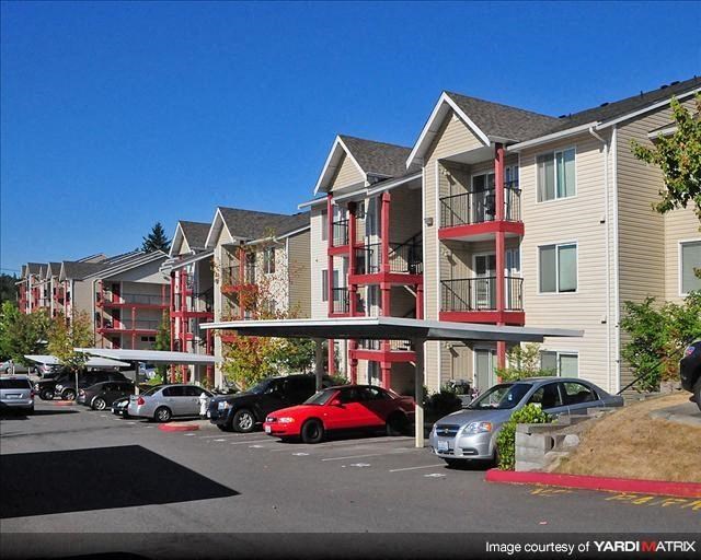 a row of apartment buildings with cars parked in a parking lot