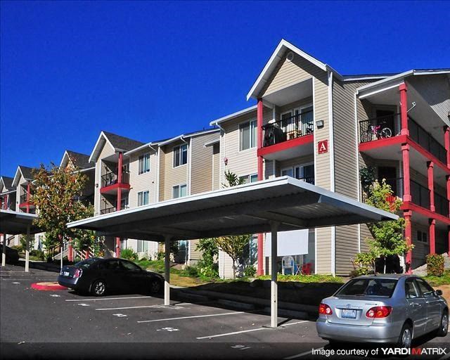 an apartment building with cars parked in a parking lot