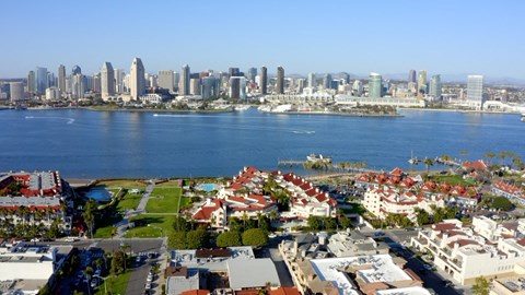 A cityscape with a body of water in the foreground and a clear sky above.