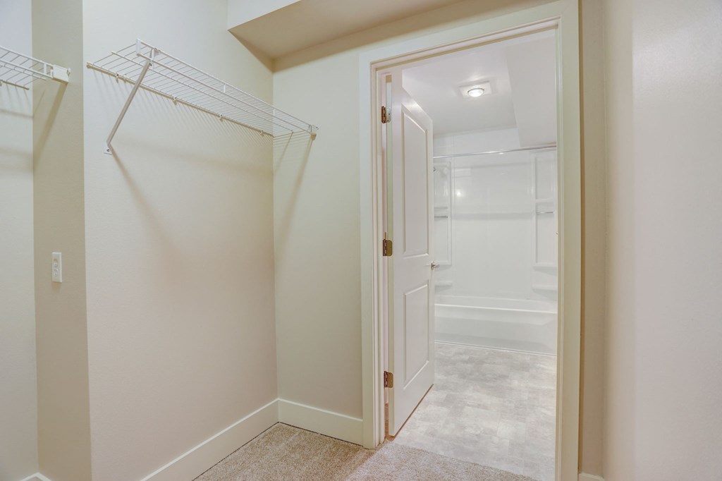 a walk in closet with a white door and a shower in the corner