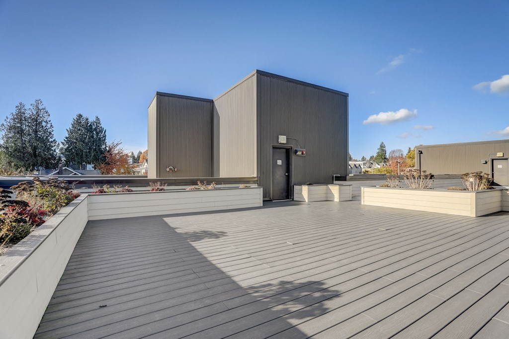 a roof terrace with a wooden deck and a building in the background