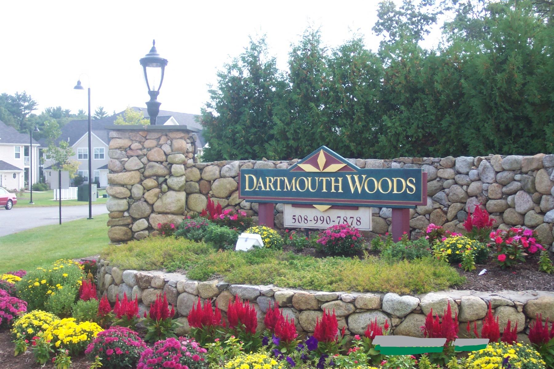 a sign for dartmouth woods in front of a stone wall and flowers