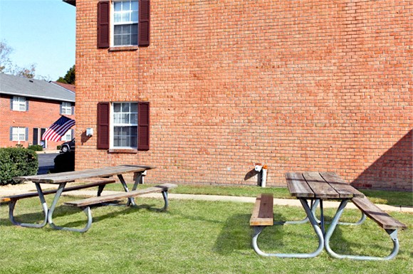two picnic tables in front of a brick building