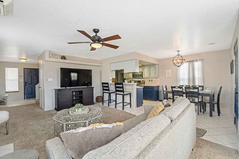 a living room and kitchen with a couch and a ceiling fan