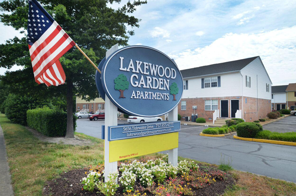 a sign for lakewood garden apartments with an flag