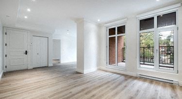 an empty living room with white walls and large windows