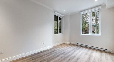 a white room with a wooden floor and two windows