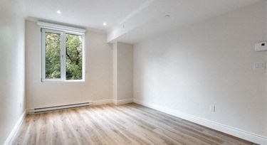 an empty room with a window and wooden floors