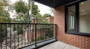 a balcony with a black railing and a brick building