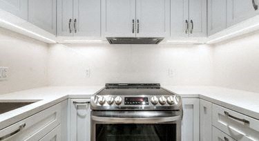 a white kitchen with a stove and white cabinets