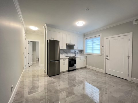 A kitchen with white cabinets and a tiled floor.