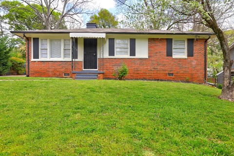 A red brick house with a black front door and white trim.