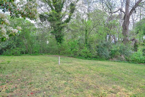 A grassy field with a white post in the middle and trees in the background.