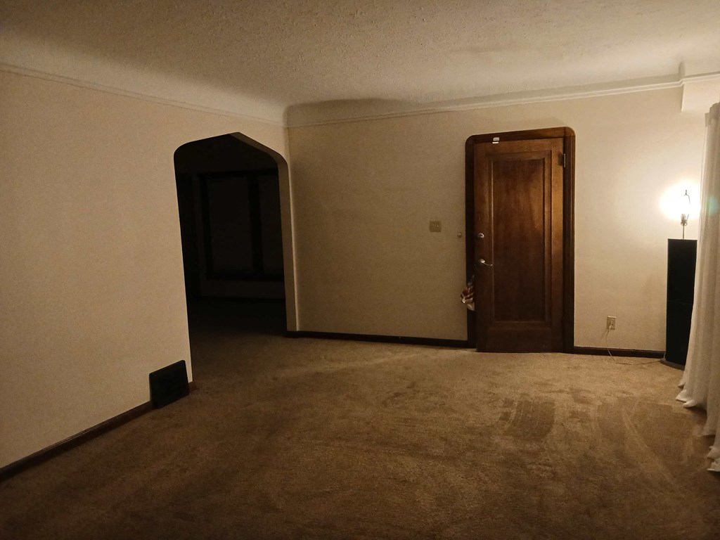 the living room is empty and the door to the bedroom is open