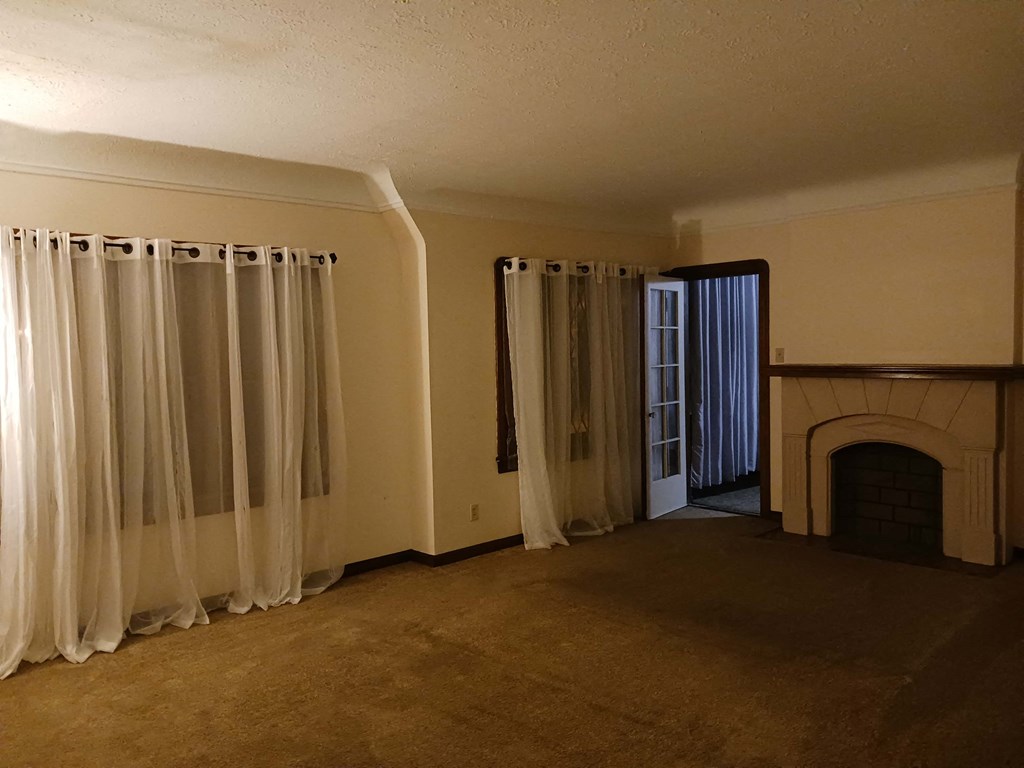 an empty living room with a fireplace and curtains