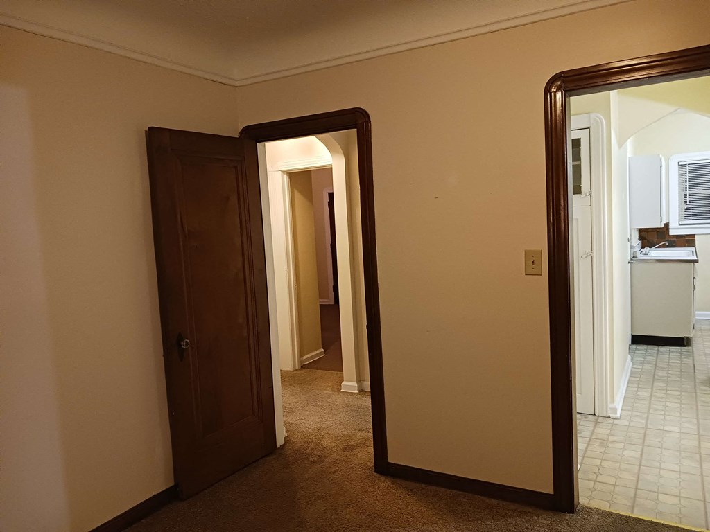 a room with a mirror and a door to a kitchen