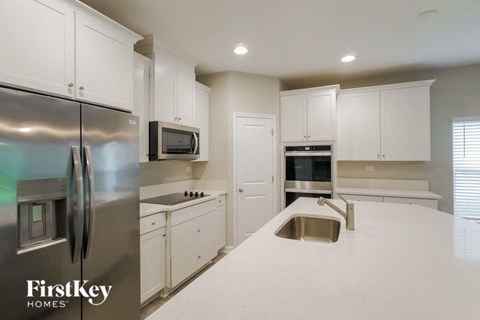 a white kitchen with stainless steel appliances and white counter tops