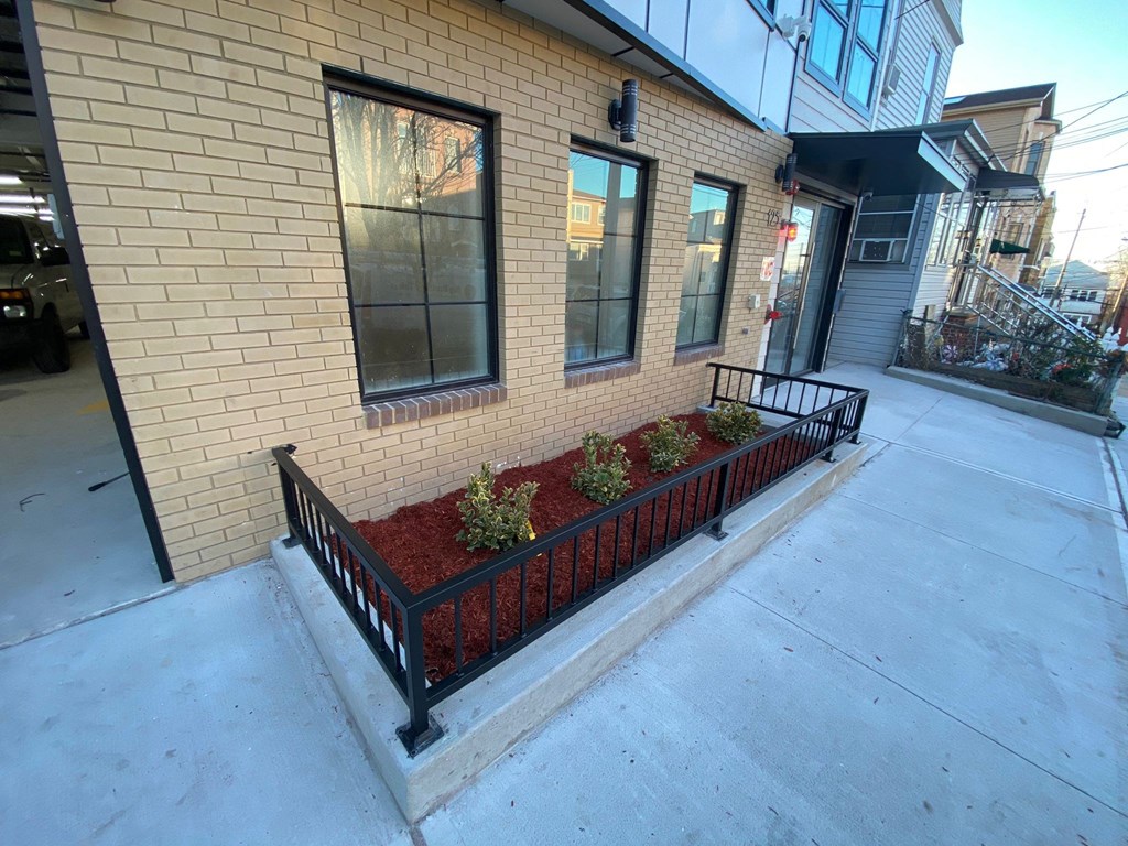 the front of a brick building with a balcony with plants