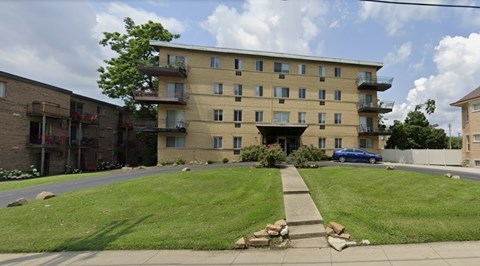 A large apartment building with a blue car parked in front.