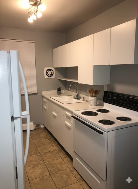 A white kitchen with a stove, sink, and refrigerator.