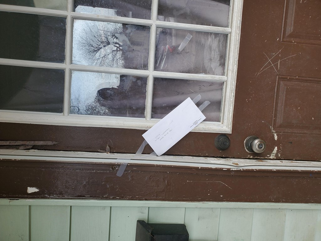 a note is taped to the window of a door