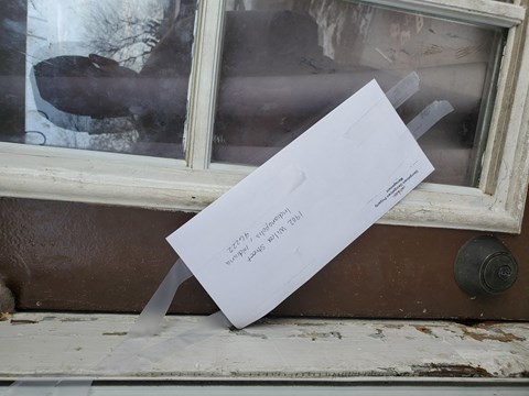 a piece of paper taped to a window with a person reflected in it