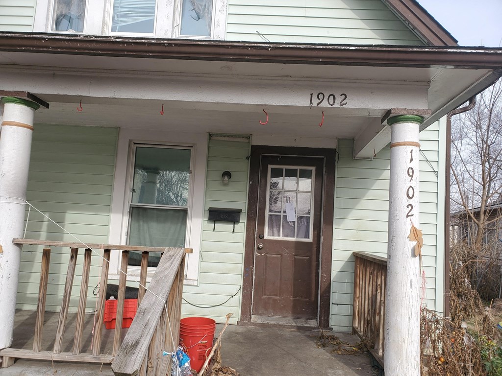 the front of a green house with a porch and a brown door